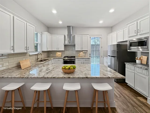 a kitchen with stainless steel appliances granite countertop a table chairs sink refrigerator and microwave