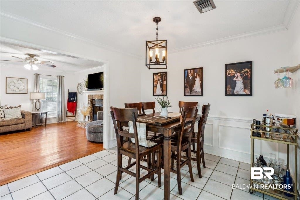 3616 Vista Ridge Drive Mobile, AL 36693 - Photo 8 of 20 Dining space with crown molding, ceiling fan with notable chandelier, light tile patterned floors, and a brick fireplace