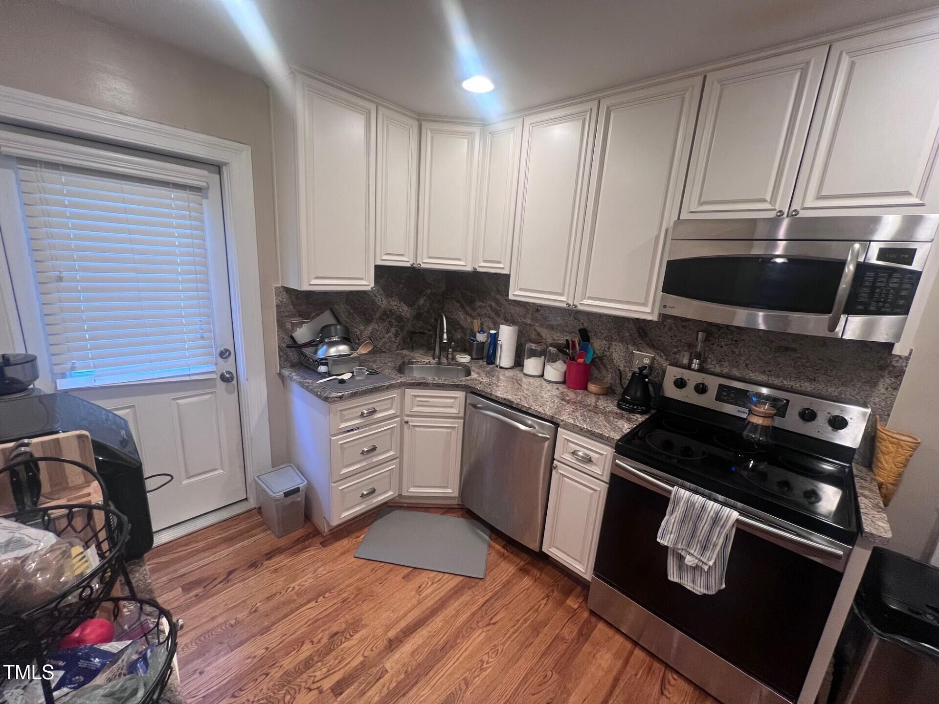2260 The Circle Raleigh, NC 27608 - Photo 3 of 9 a kitchen with granite countertop a stove a sink and dishwasher wooden cabinets with granite countertops