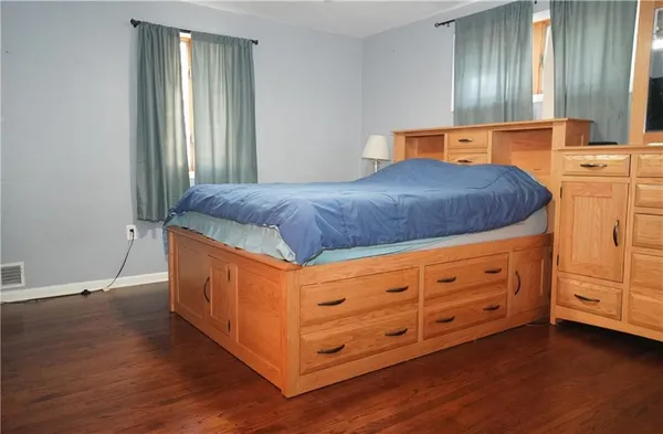 a spacious bedroom with a bed and wooden floor