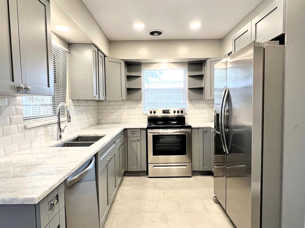 2489 Del Rio Way Dunedin, FL 34698 - Photo 8 of 24 a kitchen with stainless steel appliances granite countertop a sink stove and refrigerator