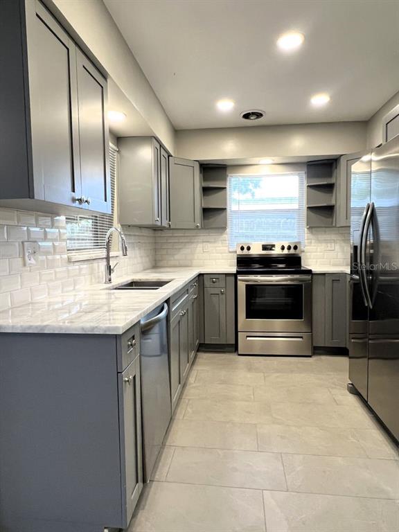 2489 Del Rio Way Dunedin, FL 34698 - Photo 9 of 24 a kitchen with stainless steel appliances granite countertop a sink counter space cabinets and a large window