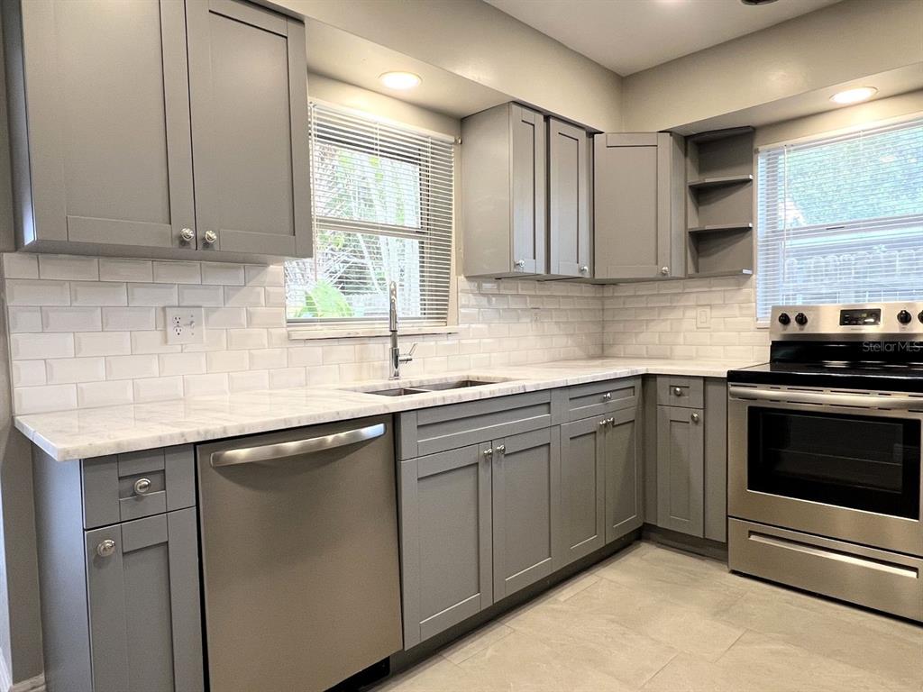 2489 Del Rio Way Dunedin, FL 34698 - Photo 10 of 24 a kitchen with stainless steel appliances granite countertop a sink stove and cabinets