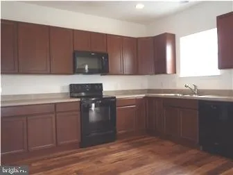 a kitchen with granite countertop a sink cabinets and stainless steel appliances