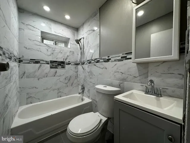 a bathroom with a toilet a sink a mirror a bathtub and vanity