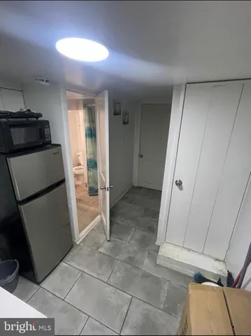 a view of a refrigerator in kitchen and an empty room