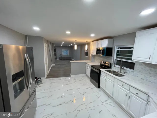 a large kitchen with stainless steel appliances kitchen island granite countertop a refrigerator and a stove top oven