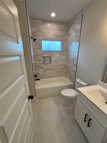 a bathroom with a granite countertop bathtub shower sink vanity and toilet