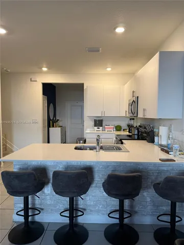 a living room with stainless steel appliances furniture and kitchen view