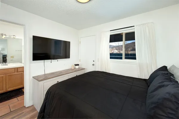 a bedroom with a bed and a flat tv screen on the dresser