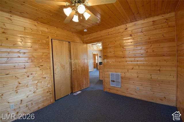 1129 Ponderosa Road, Unit 40 Hatch, UT 84735 - Photo 29 of 47 Wood-paneled walls and ceiling, ceiling fan with integrated lighting, two light-toned wood doors, and dark carpet flooring