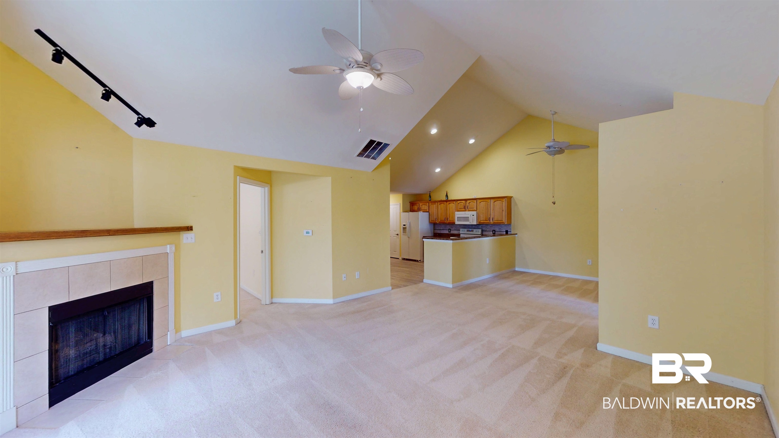 303 Wyld Palms Drive, Unit 303 Foley, AL 36535 - Photo 7 of 36 Unfurnished living room featuring a tile fireplace, light carpet, a ceiling fan, high vaulted ceiling, and rail lighting