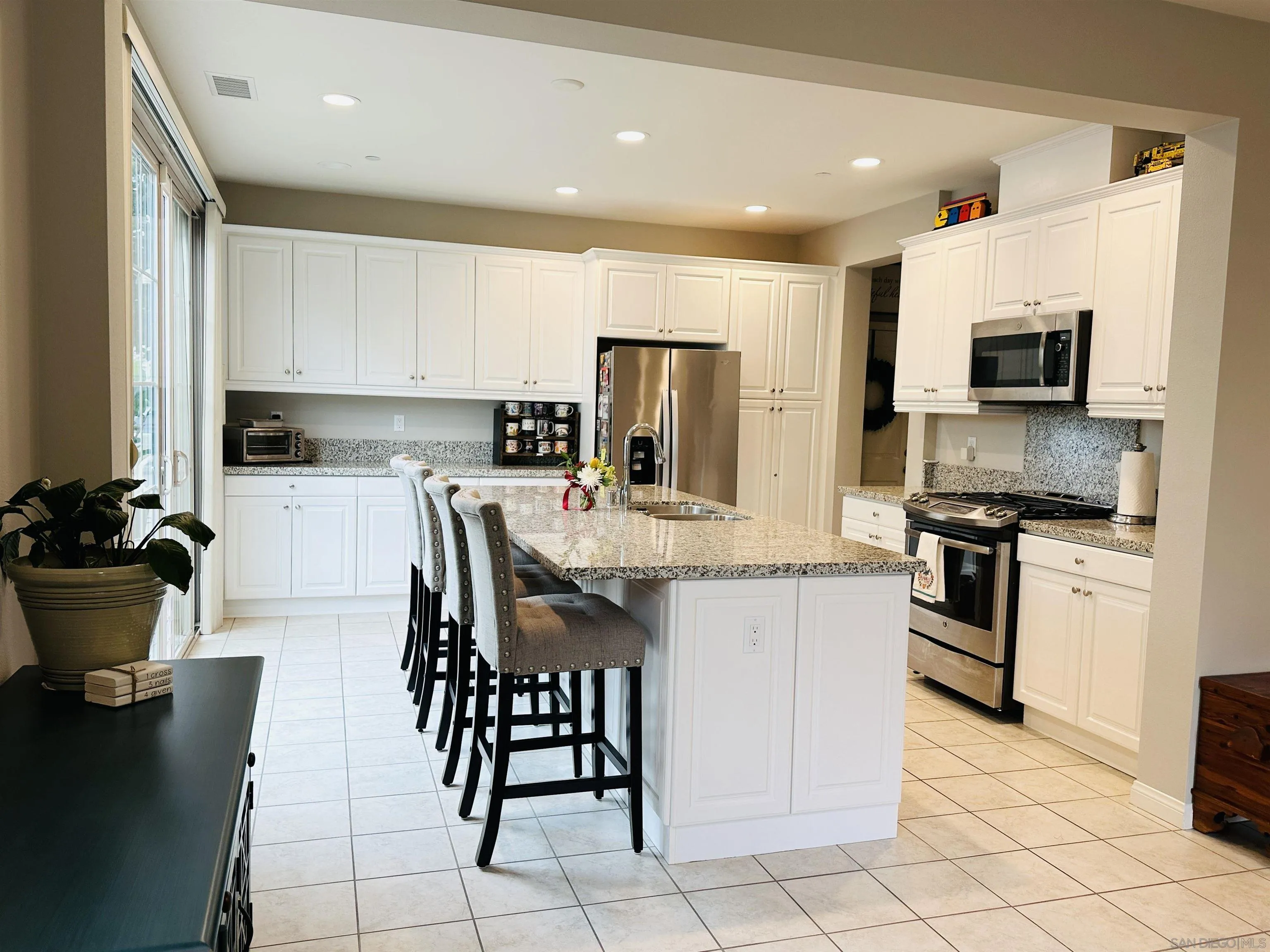 4309 Star Path Way, Unit 2 Oceanside, CA 92056 - Photo 4 of 32 a kitchen with stainless steel appliances kitchen island granite countertop a stove a sink a microwave a dining table and chairs