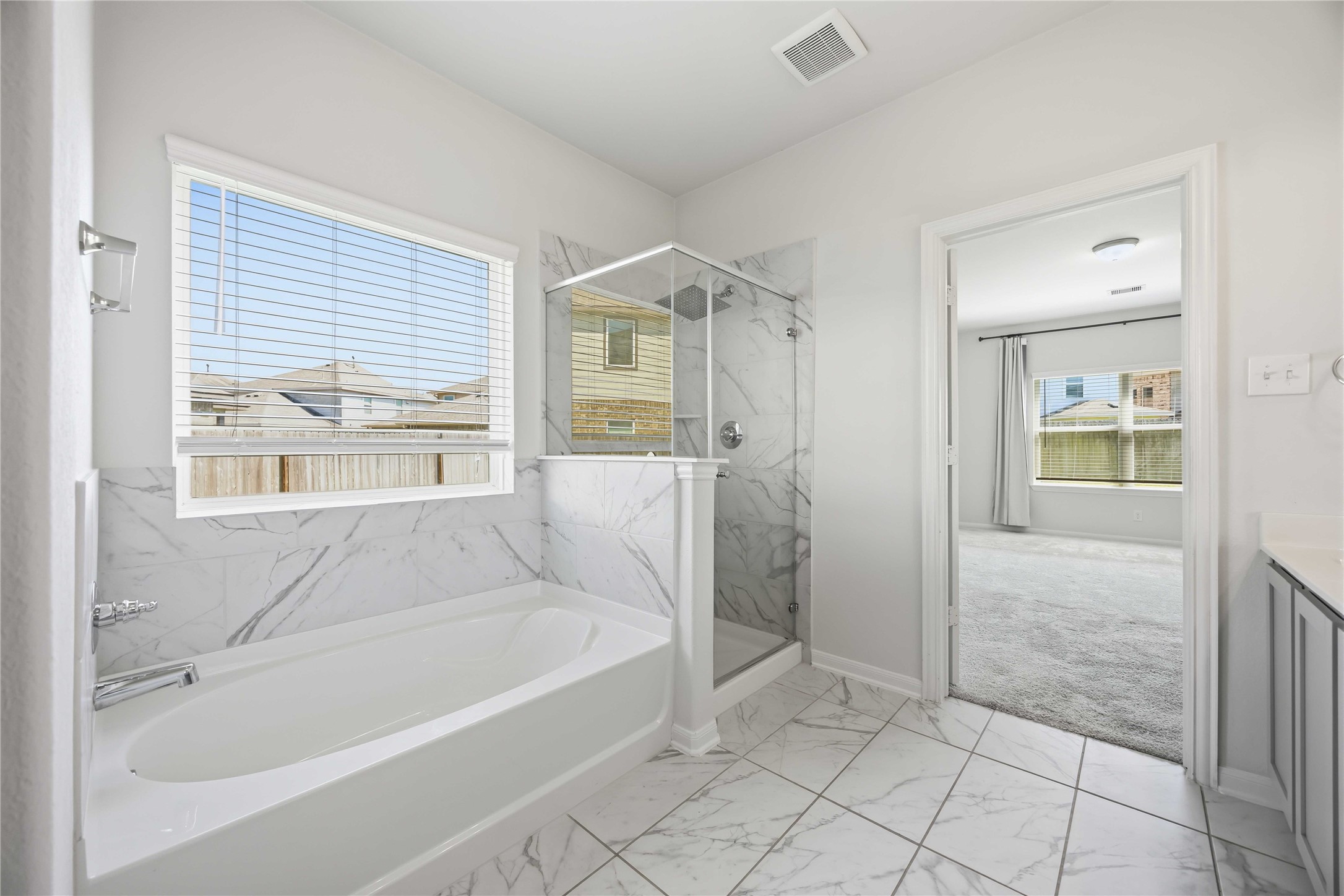 2402 Mount Dana Drive Rosharon, TX 77583 - Photo 17 of 28 Luxurious bathroom featuring elegant marble tile, a spacious soaking tub, and a sleek glass-enclosed shower, with ample natural light streaming in through large windows.