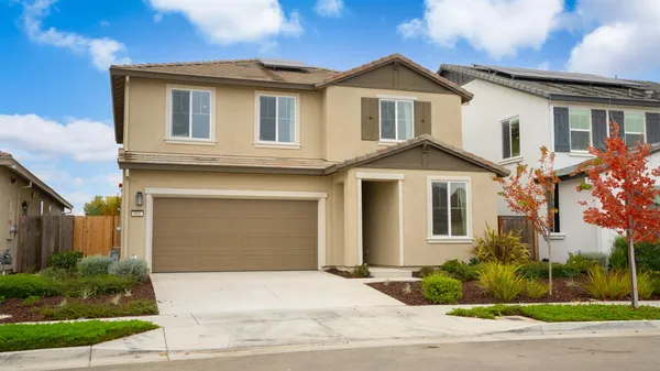 a white house with a small yard and a large parking space