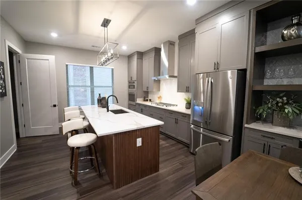 a kitchen with stainless steel appliances kitchen island a table chairs in it and wooden floors