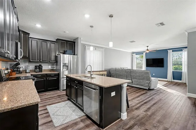 a large kitchen with stainless steel appliances kitchen island granite countertop a stove refrigerator and a sink