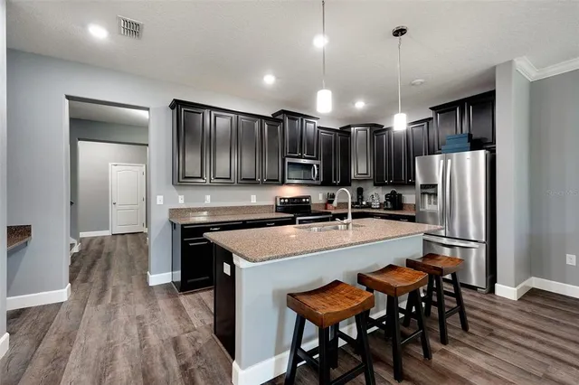 a large kitchen with a table chairs refrigerator and microwave