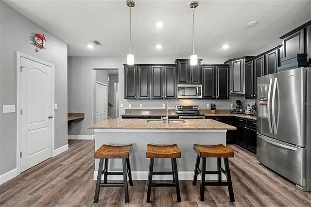 a kitchen with stainless steel appliances granite countertop a refrigerator a stove top oven a sink dishwasher and white cabinets with wooden floor