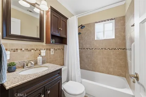 a bathroom with a granite countertop sink toilet mirror and bathtub