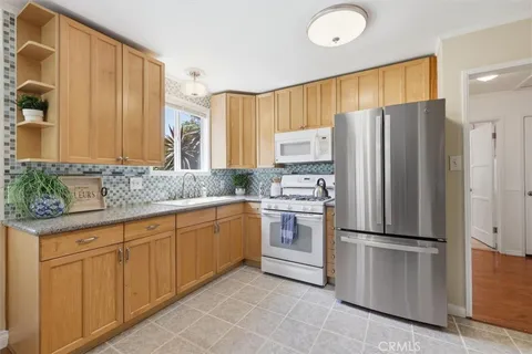 a kitchen with granite countertop stainless steel appliances a refrigerator sink and microwave