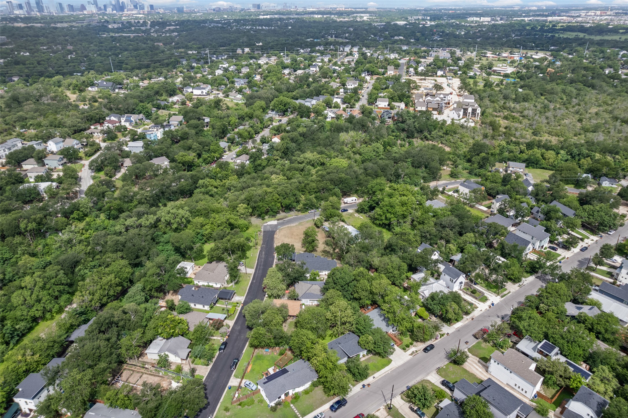 1201 Fort Branch Boulevard Austin, TX 78721 - Photo 5 of 19 An aerial perspective reveals a tree-lined neighborhood with a backdrop of a distant cityscape.