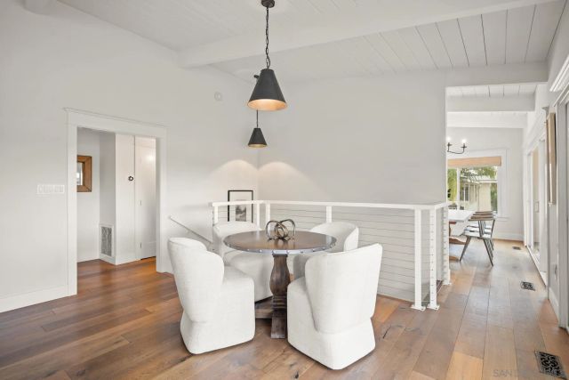 a dining room with wooden floor a glass table and chairs