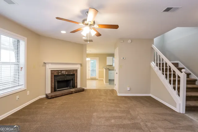 a view of an empty room with chandelier fan and fire place