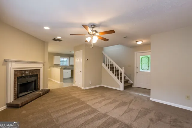 a view of an empty room with a fireplace and a chandelier fan