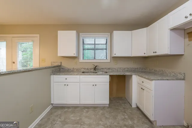 a kitchen with granite countertop white cabinets stainless steel appliances a sink and a window