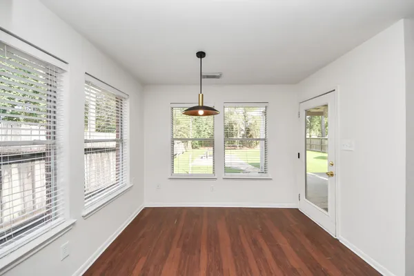 a view of an empty room with wooden floor and a window