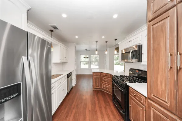 a kitchen with stainless steel appliances a refrigerator a stove a sink and a stove with wooden floor