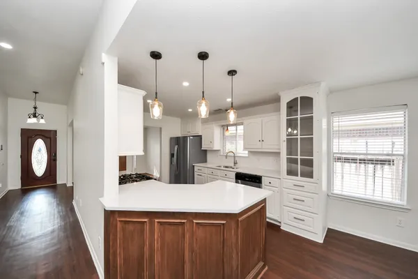 a kitchen with a refrigerator a stove a sink dishwasher with wooden floor and cabinets next to a window
