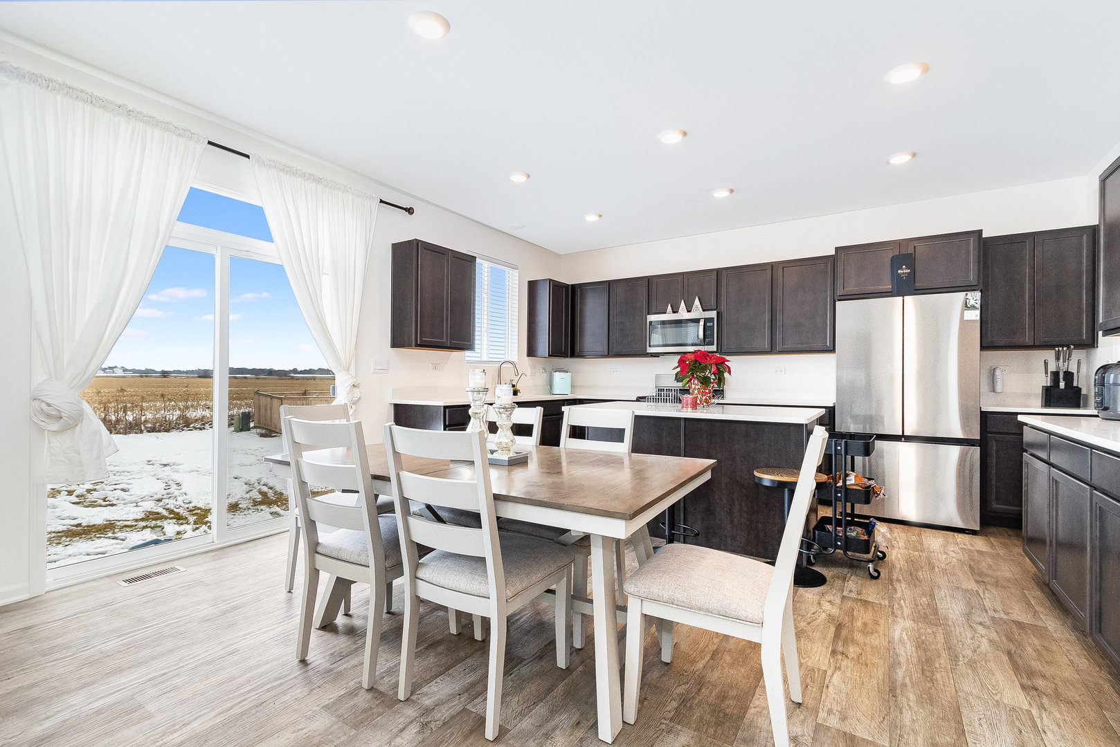 382 Hemlock Lane Oswego, IL 60543 - Photo 3 of 17 a kitchen with a dining table chairs refrigerator and microwave