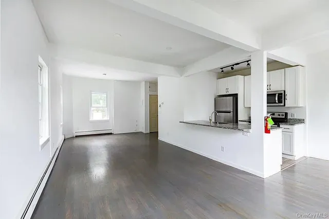 a view of empty room with wooden floor and windows