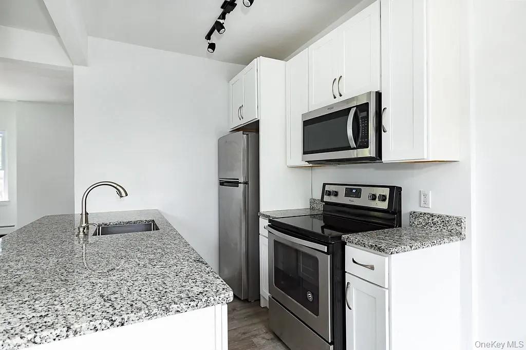 144 Union Street, Unit 4 Poughkeepsie, NY 12601 - Photo 4 of 7 a kitchen with granite countertop a stove top oven microwave and refrigerator