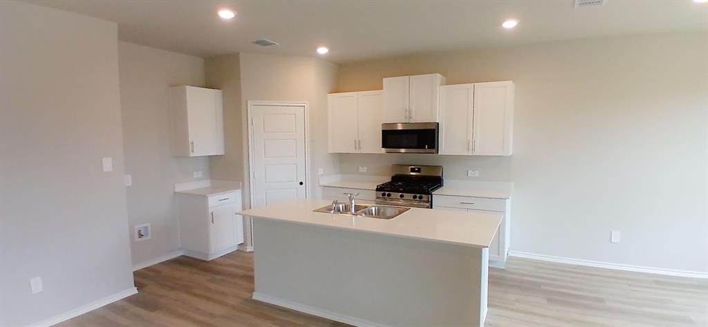 312 Perk Street Keene, TX 76059 - Photo 11 of 13 a white kitchen with a sink a microwave a refrigerator and cabinets