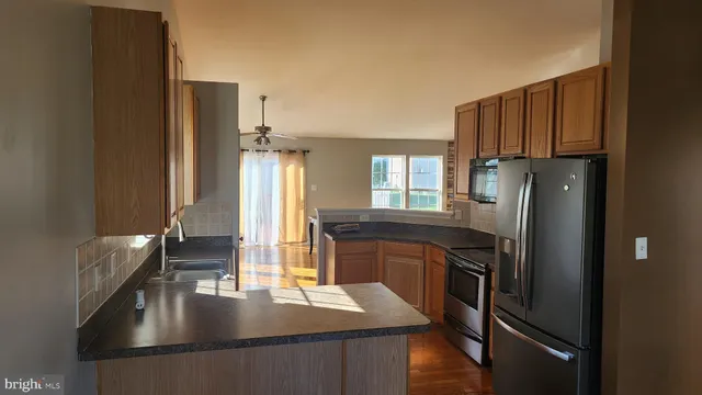 a kitchen with kitchen island granite countertop a refrigerator a stove and a sink