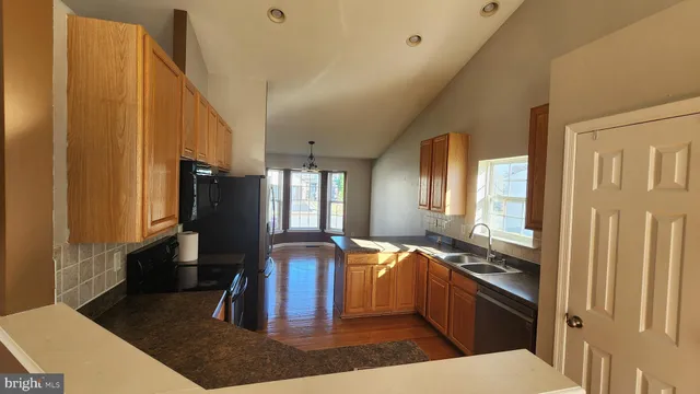 a kitchen with stainless steel appliances kitchen island granite countertop a refrigerator a stove and a sink with wooden floor