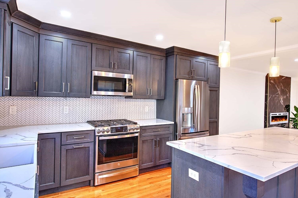 3 Wensley Street, Unit 1 Boston, MA 02120 - Photo 17 of 40 a kitchen with granite countertop wooden cabinets and stainless steel appliances