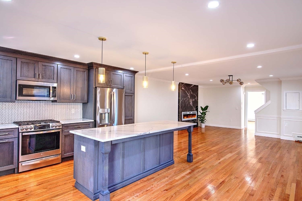 3 Wensley Street, Unit 1 Boston, MA 02120 - Photo 18 of 40 a kitchen with stainless steel appliances kitchen island granite countertop a refrigerator a sink and wooden floor