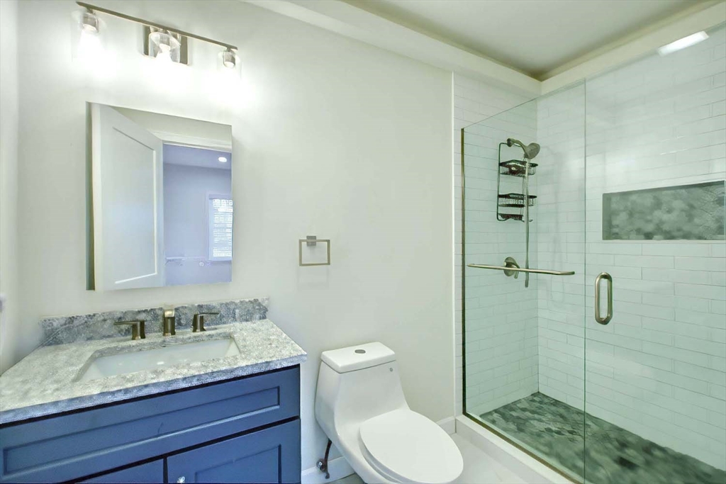 3 Wensley Street, Unit 1 Boston, MA 02120 - Photo 28 of 40 a bathroom with a granite countertop sink toilet a mirror and shower