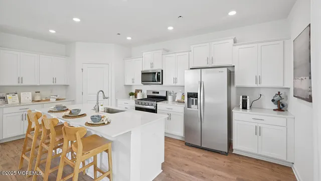 a kitchen with stainless steel appliances granite countertop a stove top oven a sink dishwasher a dining table and chairs with wooden floor