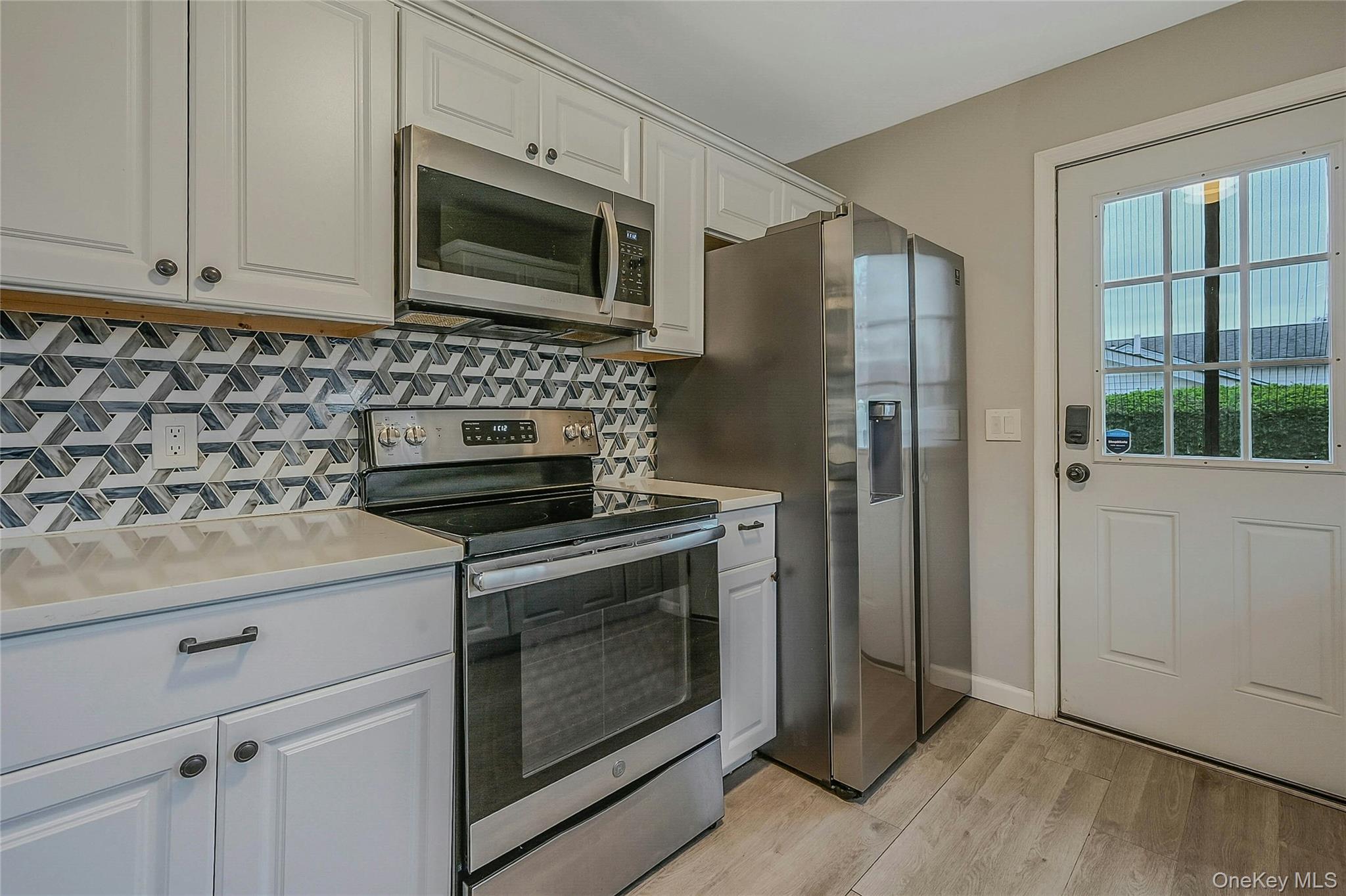 425 Blue Point Road Farmingville, NY 11738 - Photo 11 of 32 a kitchen with stainless steel appliances white cabinets and a stove top oven