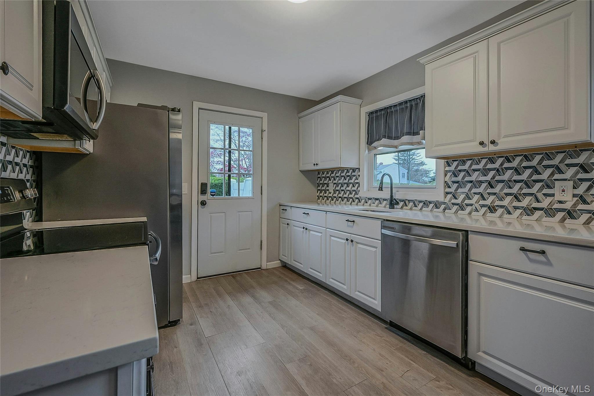 425 Blue Point Road Farmingville, NY 11738 - Photo 9 of 32 a kitchen with stainless steel appliances a sink cabinets and wooden floor