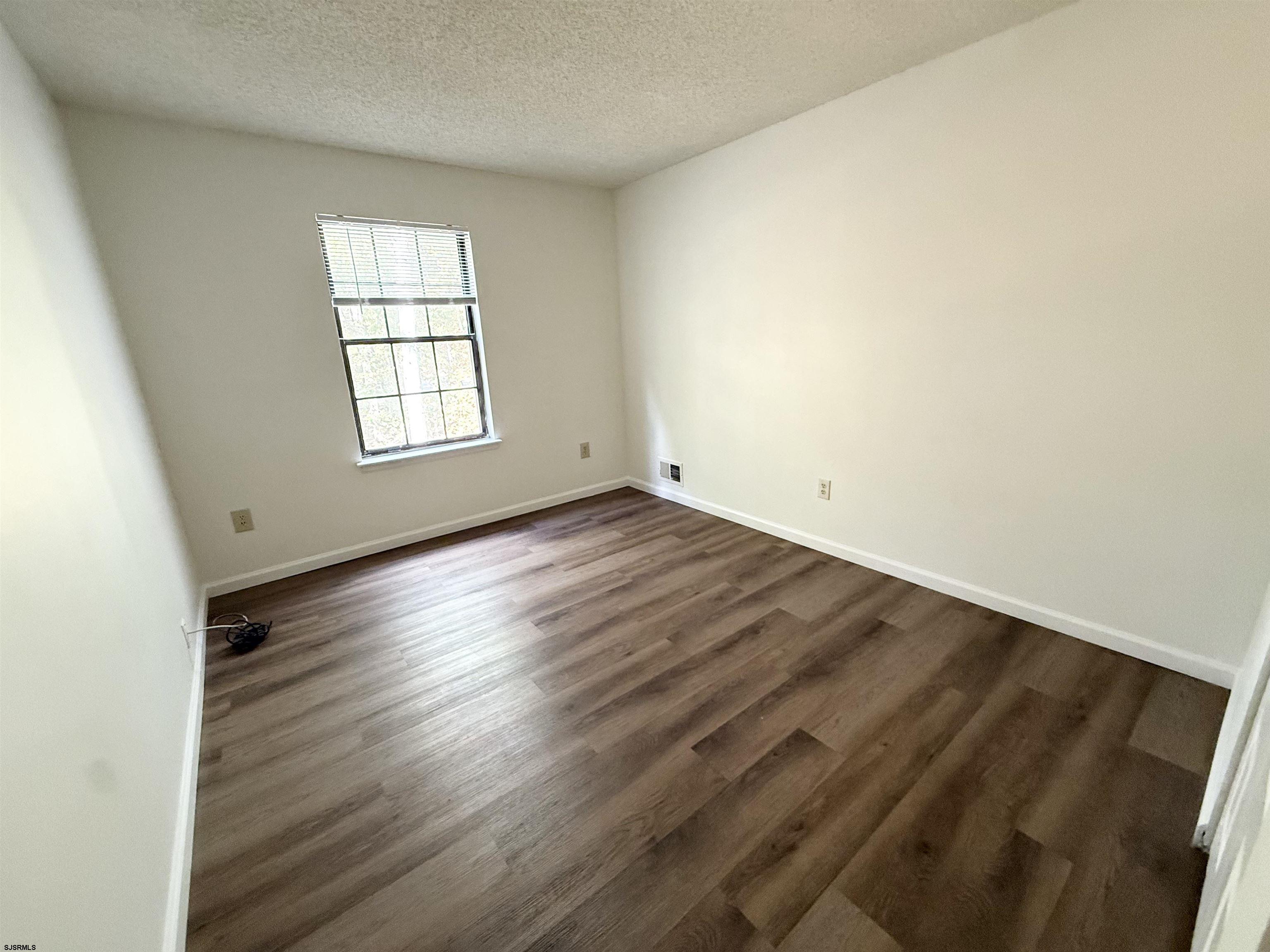11 Colonial Court, Unit 11 Galloway Township, NJ 08205 - Photo 11 of 15 an empty room with wooden floor and windows