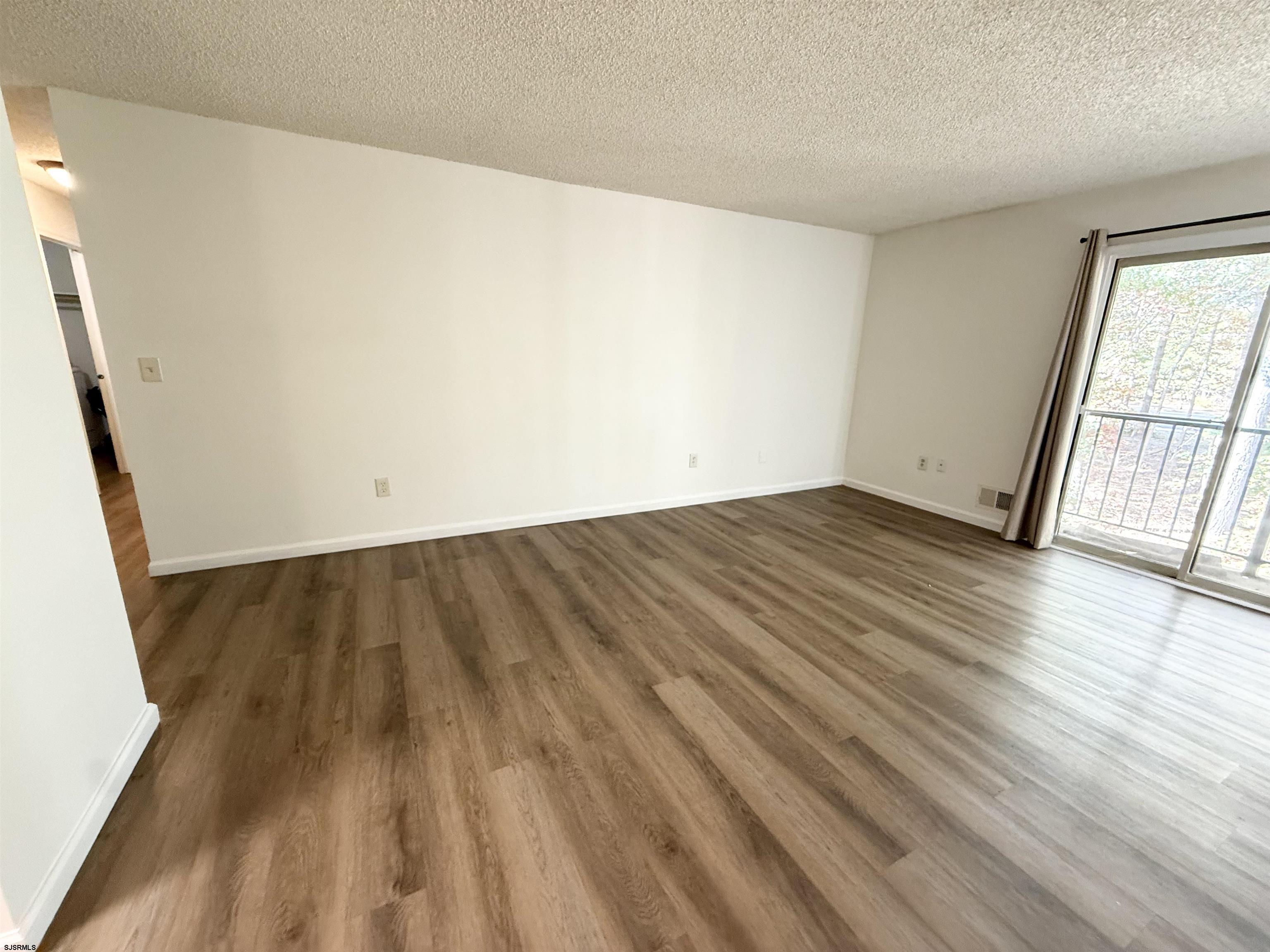 11 Colonial Court, Unit 11 Galloway Township, NJ 08205 - Photo 3 of 15 an empty room with wooden floor and windows