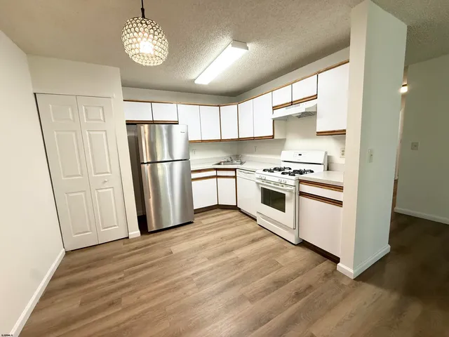 a kitchen with a refrigerator a stove a microwave and white cabinets