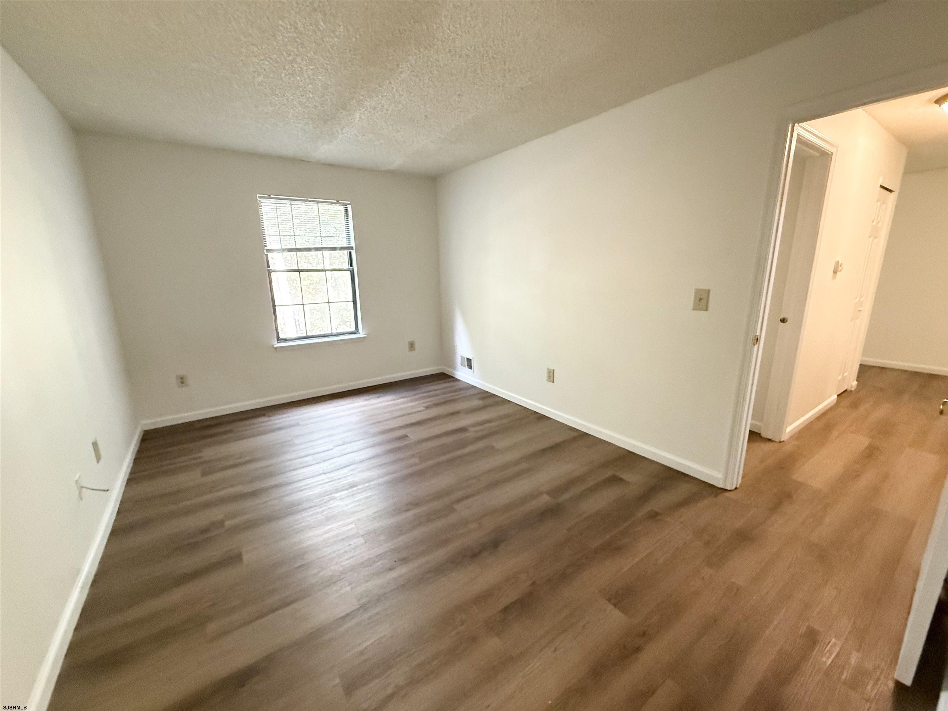 11 Colonial Court, Unit 11 Galloway Township, NJ 08205 - Photo 7 of 15 an empty room with wooden floor and windows