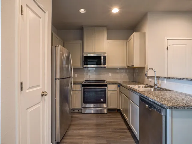 a kitchen with stainless steel appliances granite countertop a stove a refrigerator and a sink